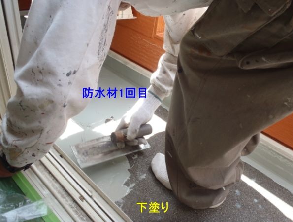 バルコニー床に防水材1回目をコテで塗り広げる作業