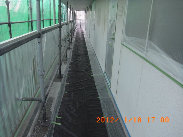 厚手の黒いシートで床を覆った2階共用通路