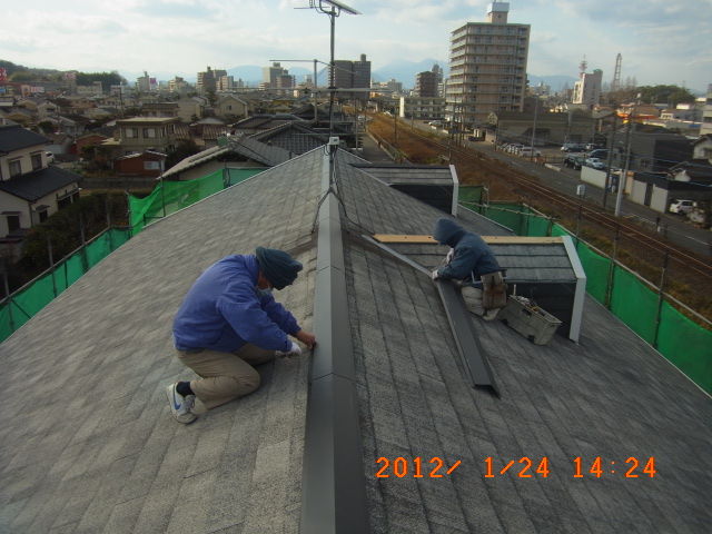 新しい棟包み板金を取り付ける職人