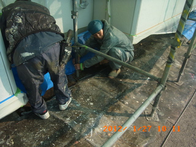 南面外壁の足元をシートで養生する作業員