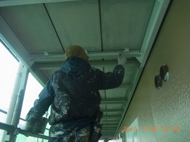 共用通路の梁を刷毛で上塗りする作業員