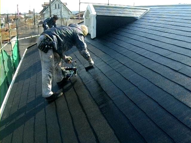 屋根の平面をローラーで上塗りする作業