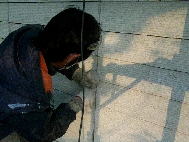 工具で外壁目地の既存シーリングを撤去する作業