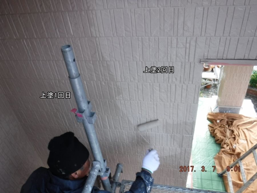 ローラーで玄関周囲の外壁に上塗り2回目を施工