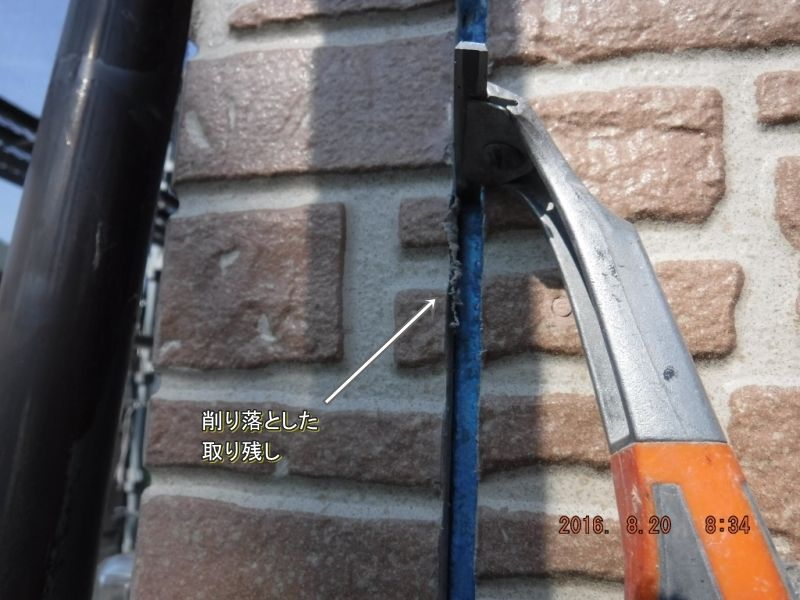 スクレーパーで目地断面に残った旧シーリングの薄膜を削り落とす作業