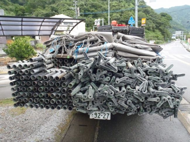 足場部材とメッシュシートを積んだトラック