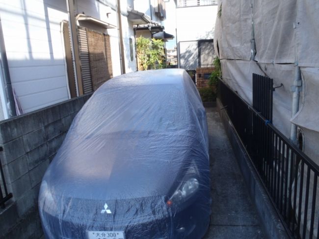 高圧洗浄に備えて専用カバーで養生した駐車車両