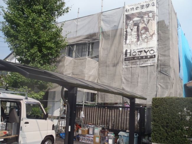 足場に北条塗装店の看板を掲げた住宅外観