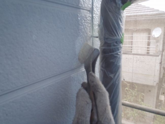 外壁の端部を刷毛で下塗りする作業