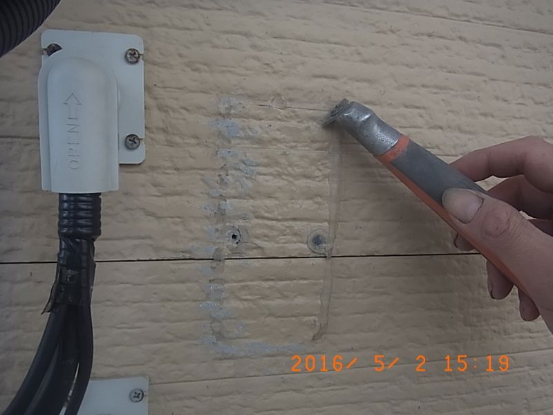 移設した器具の跡に残るシリコーンシーリングを削る手元
