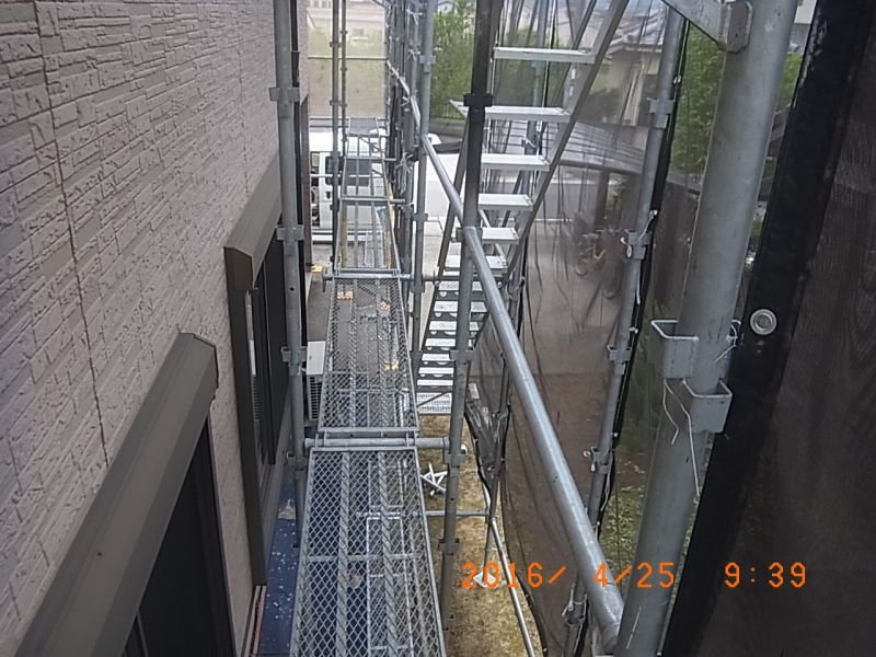外壁とメッシュシートの間の足場通路と階段