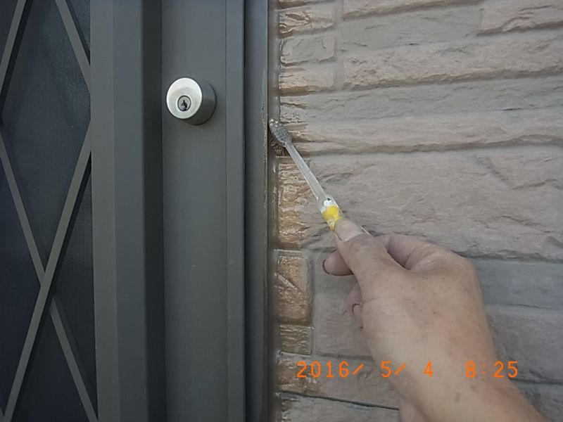 歯ブラシで玄関枠際のシーリングを清掃する作業