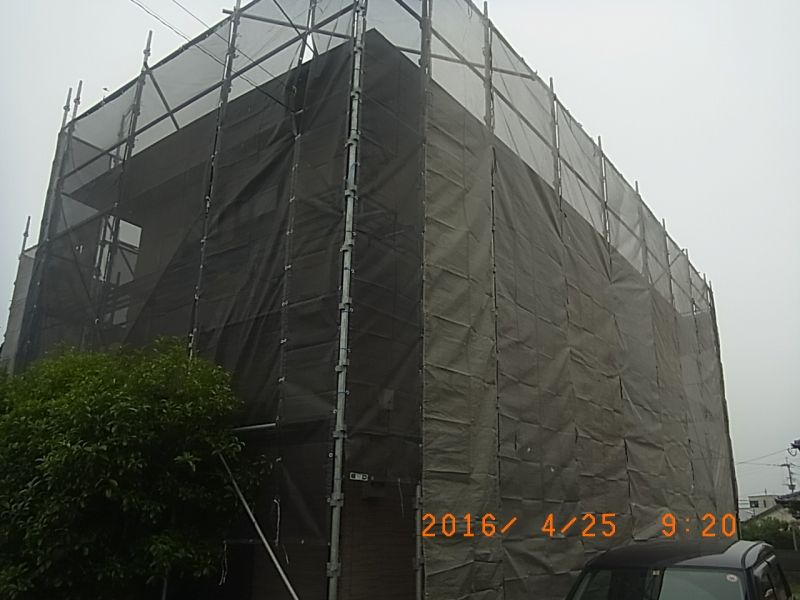 住宅の角を囲むメッシュシート付き足場