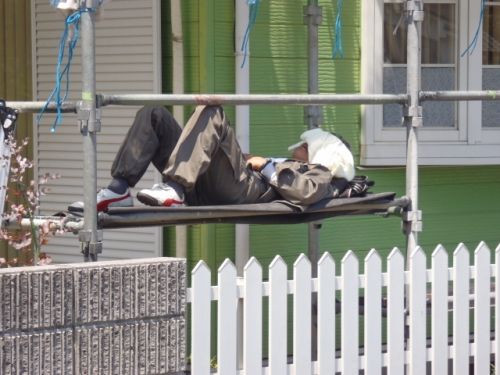 昼休みに足場の上で横になる職人