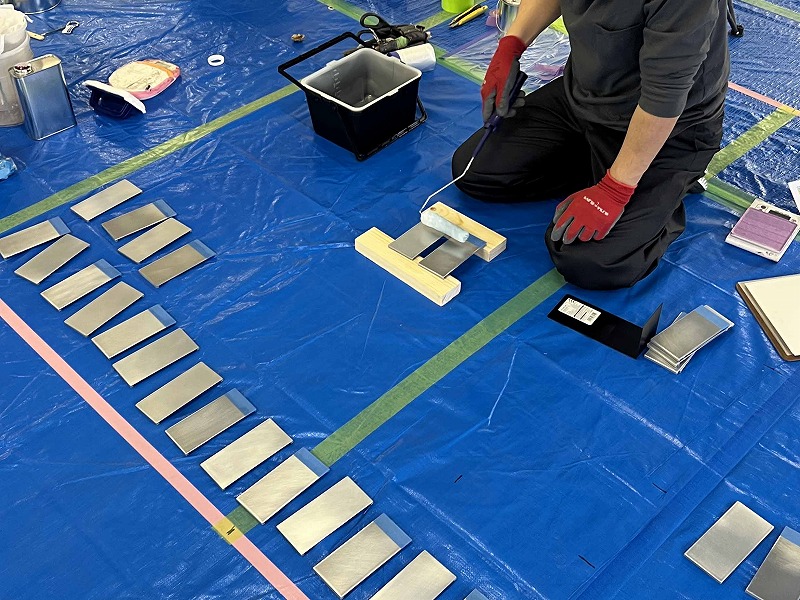 比較試験用の板にローラーで塗料を塗る作業