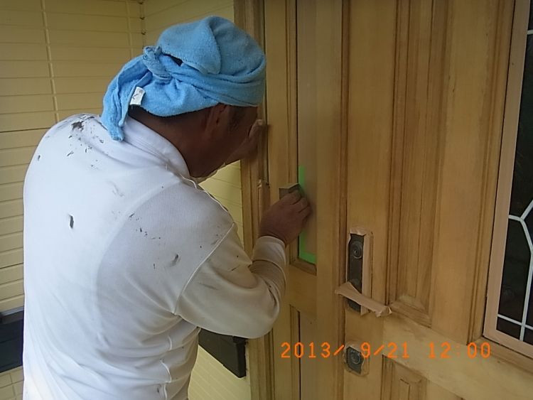 木製玄関ドアの細かな凹凸を手作業で研磨する職人