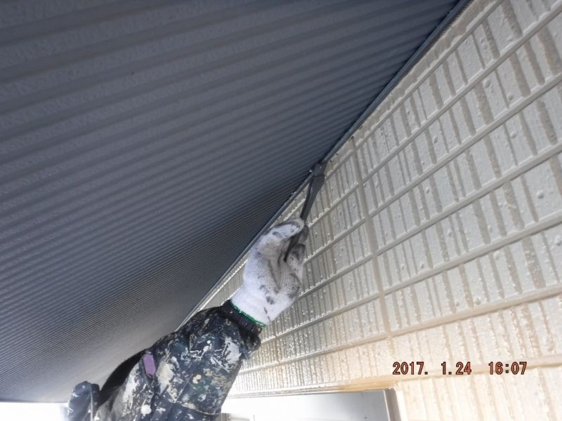 軒裏と外壁の取り合いを刷毛で手直しする作業