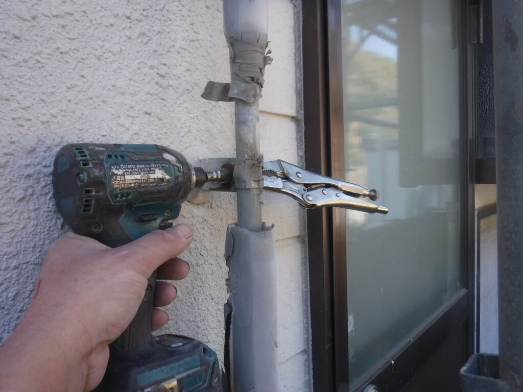工具を使って水道管の固定バンドを外す作業