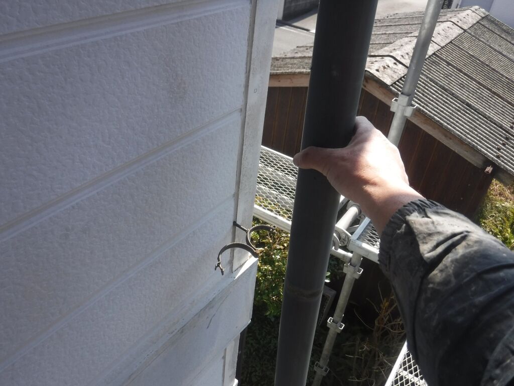 固定金具を開いて竪樋を取り外す作業