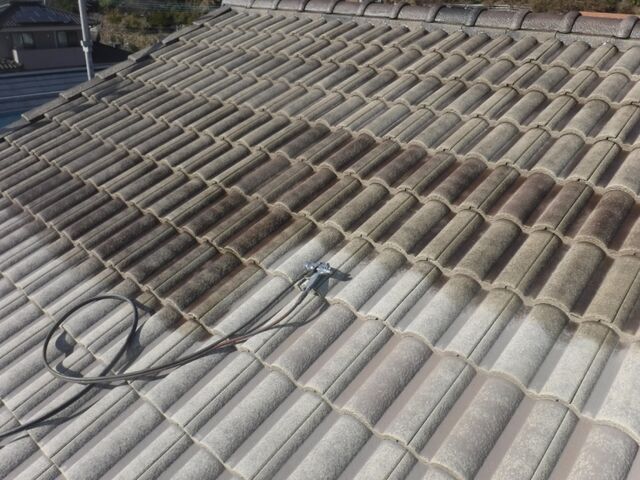 下塗り作業中のセメント瓦屋根と吹き付けガン